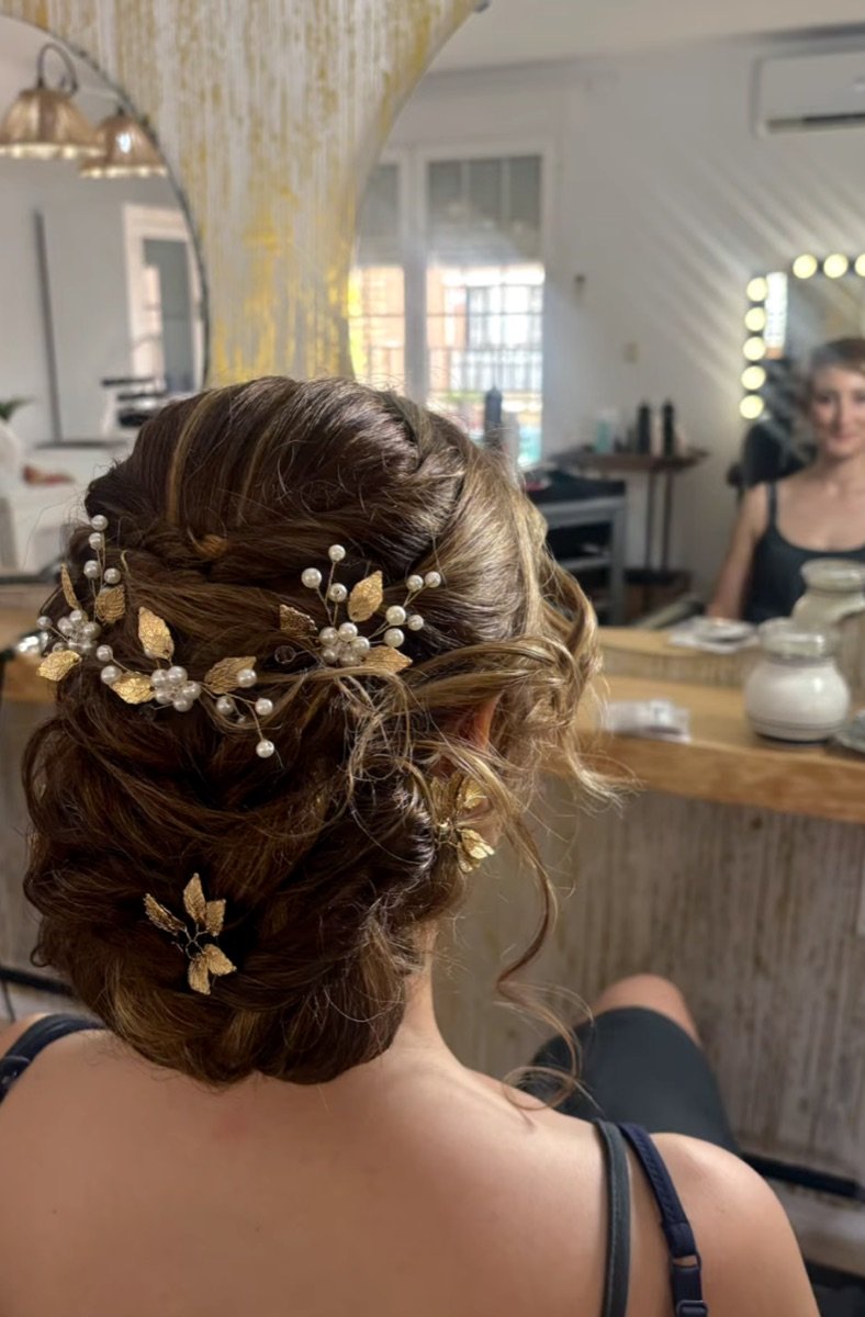 Recogido de novia con tocado dorado, con el salón al fondo